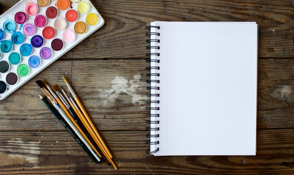 Coin de travail avec palette d’aquarelle, pinceaux et carnet ouvert