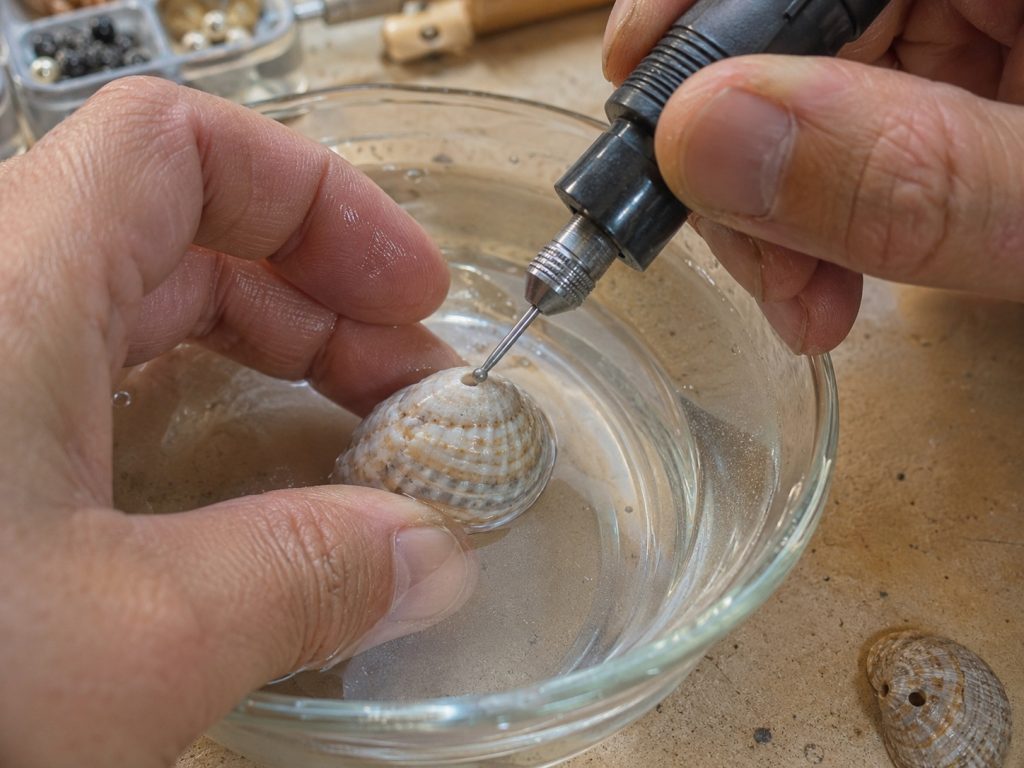 Perçage d’un coquillage à la mini-perceuse, sous quelques millimètres d’eau