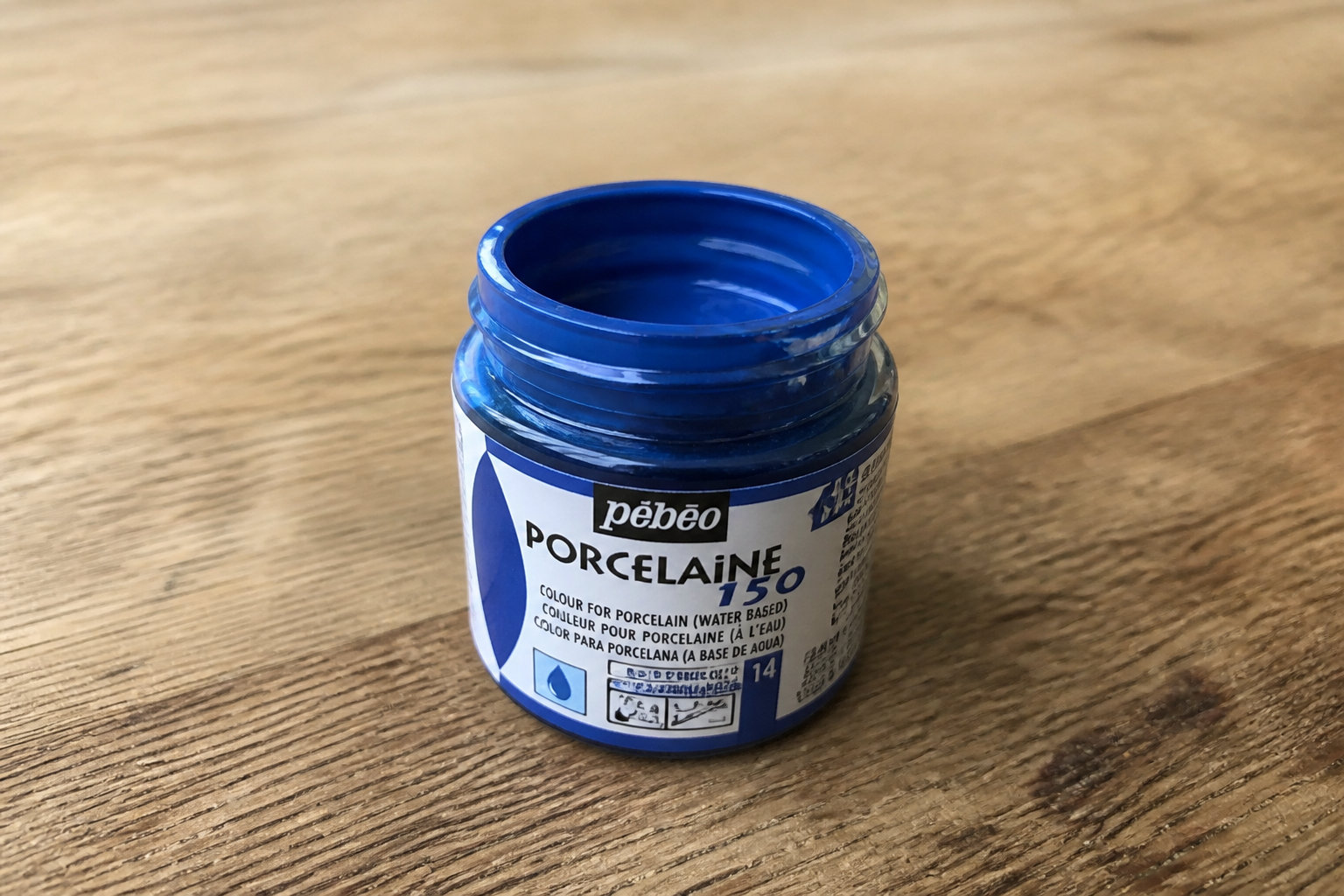 Pot de peinture Pébéo Porcelaine 150 bleu posé sur un plan de travail en bois
